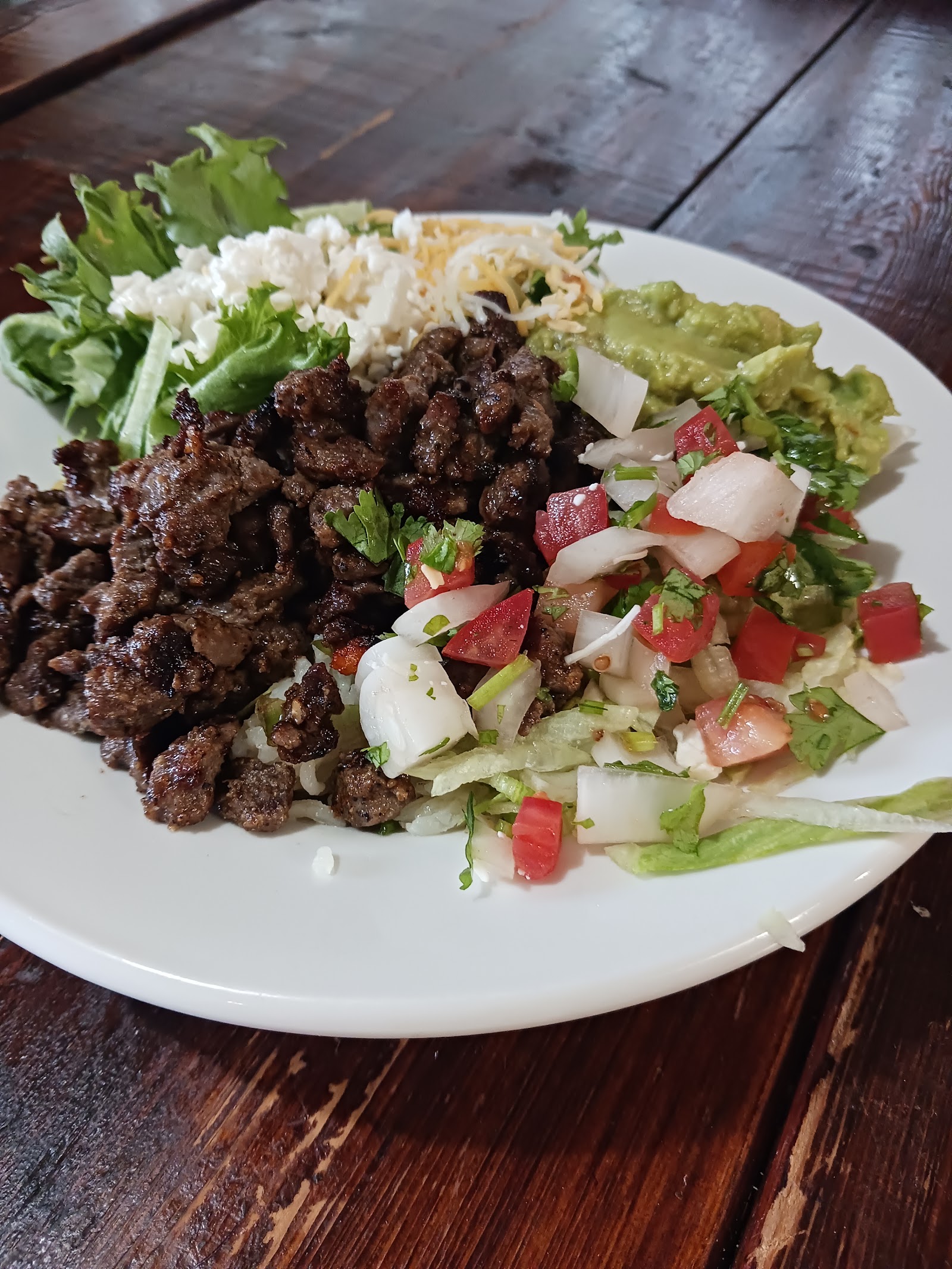 Steak plate with rice, beans, guacamole, pico de gallo, and fresh cheese