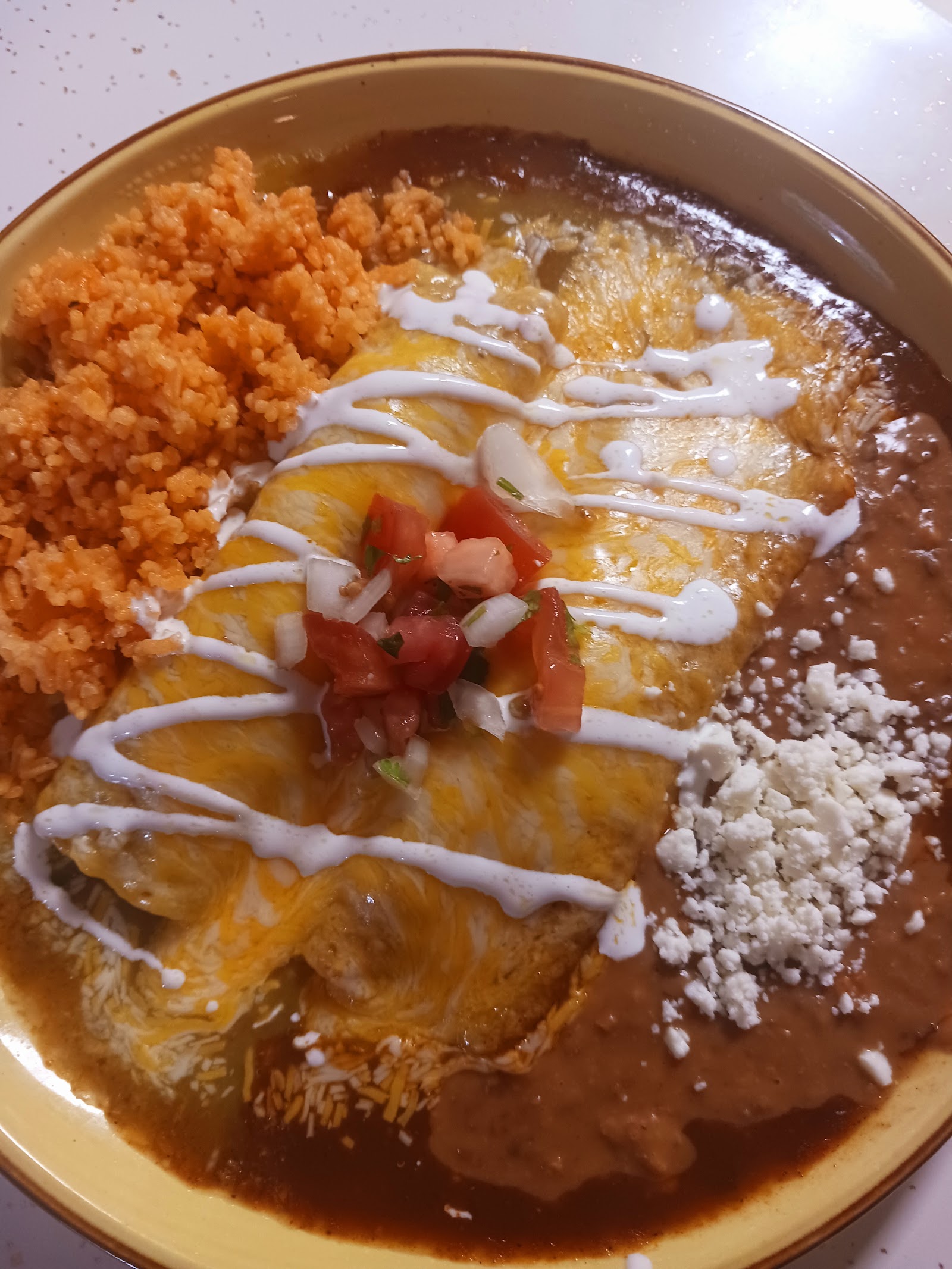 Cheese enchiladas plate with Mexican rice, refried beans, and pico de gallo