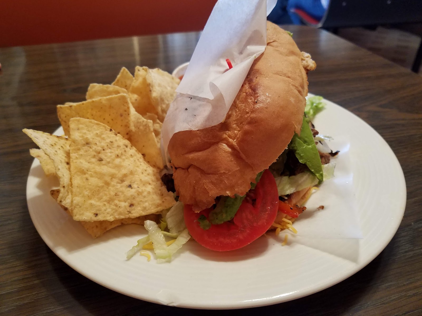 Bistro burger with lettuce, tomato, and avocado, served with tortilla chips